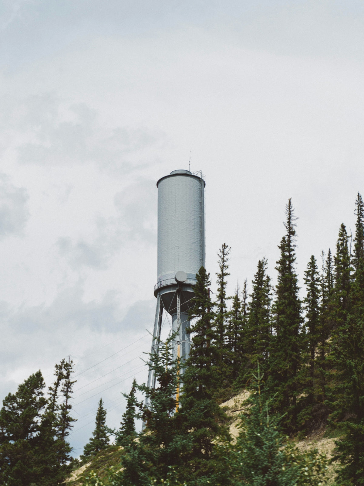 green metal water tower at the side of the mountain