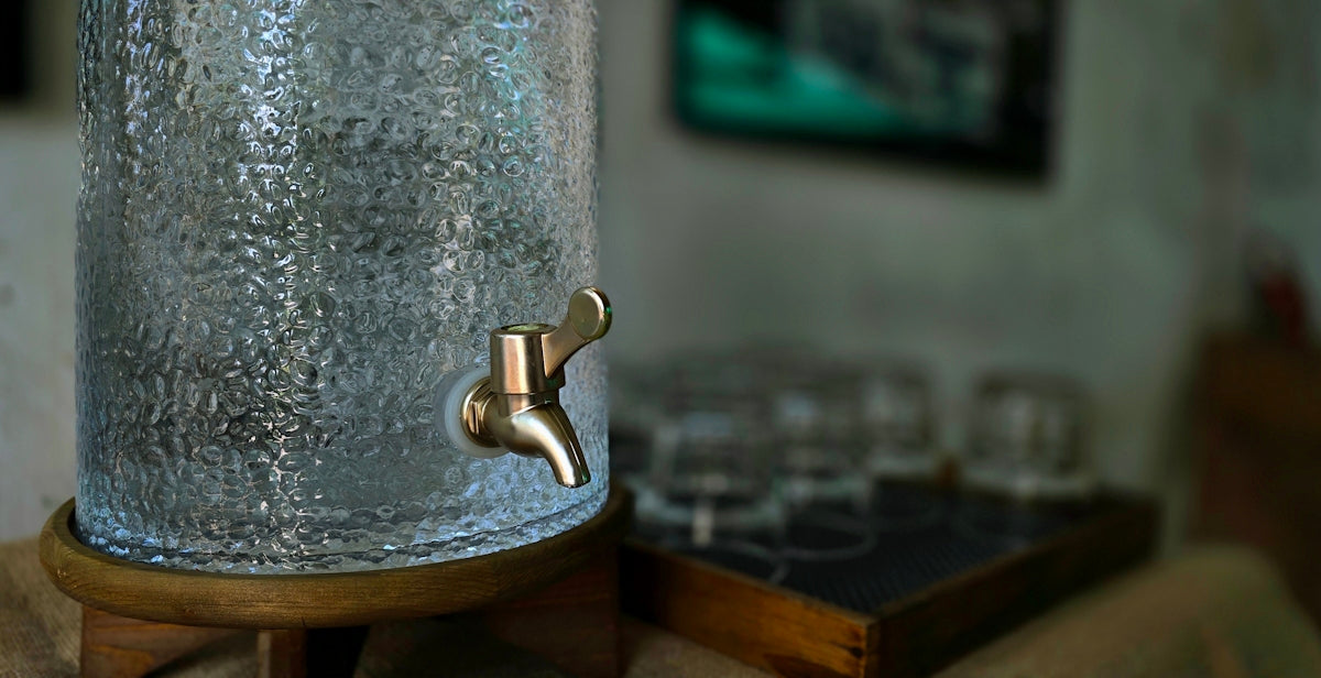 A glass water dispenser and drinking glasses.