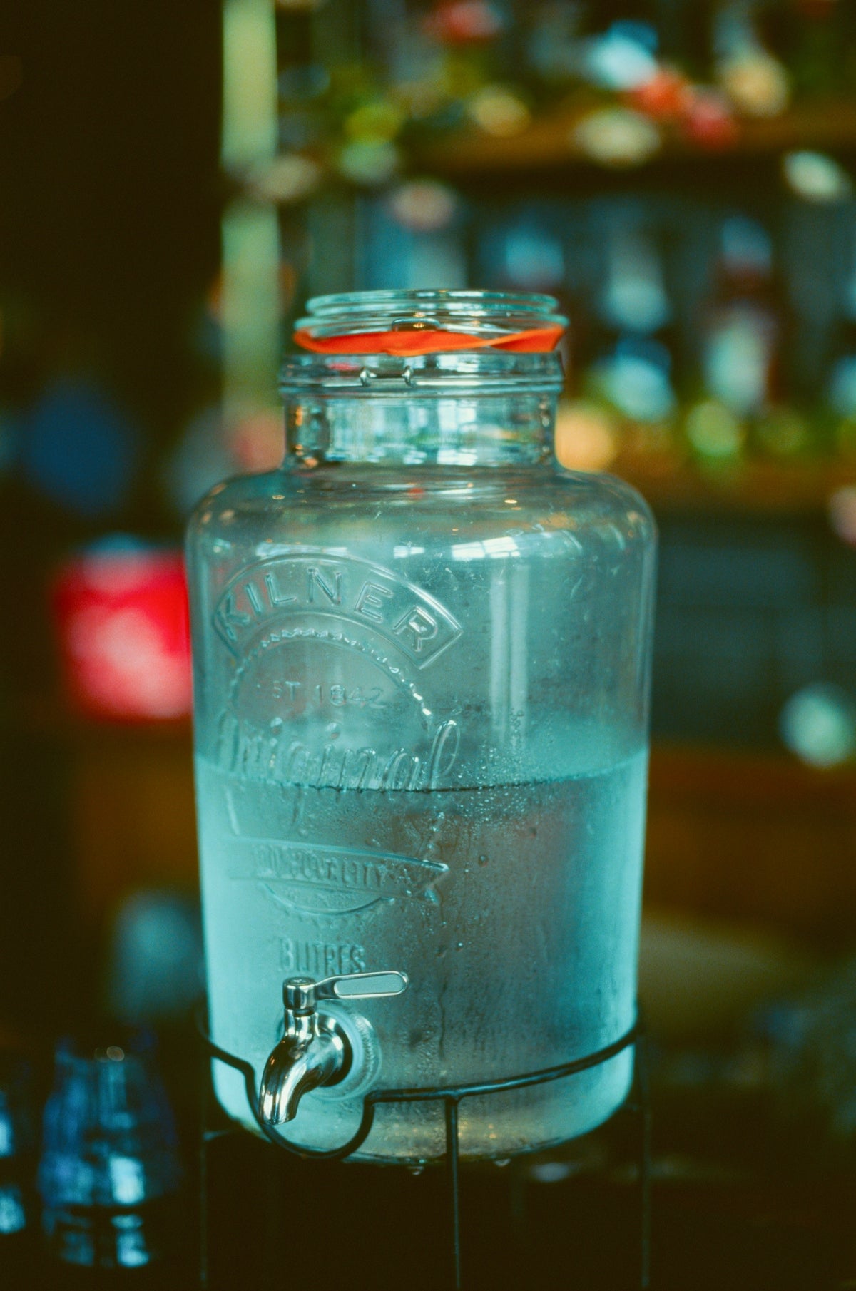 Glass beverage dispenser with tap filled with water