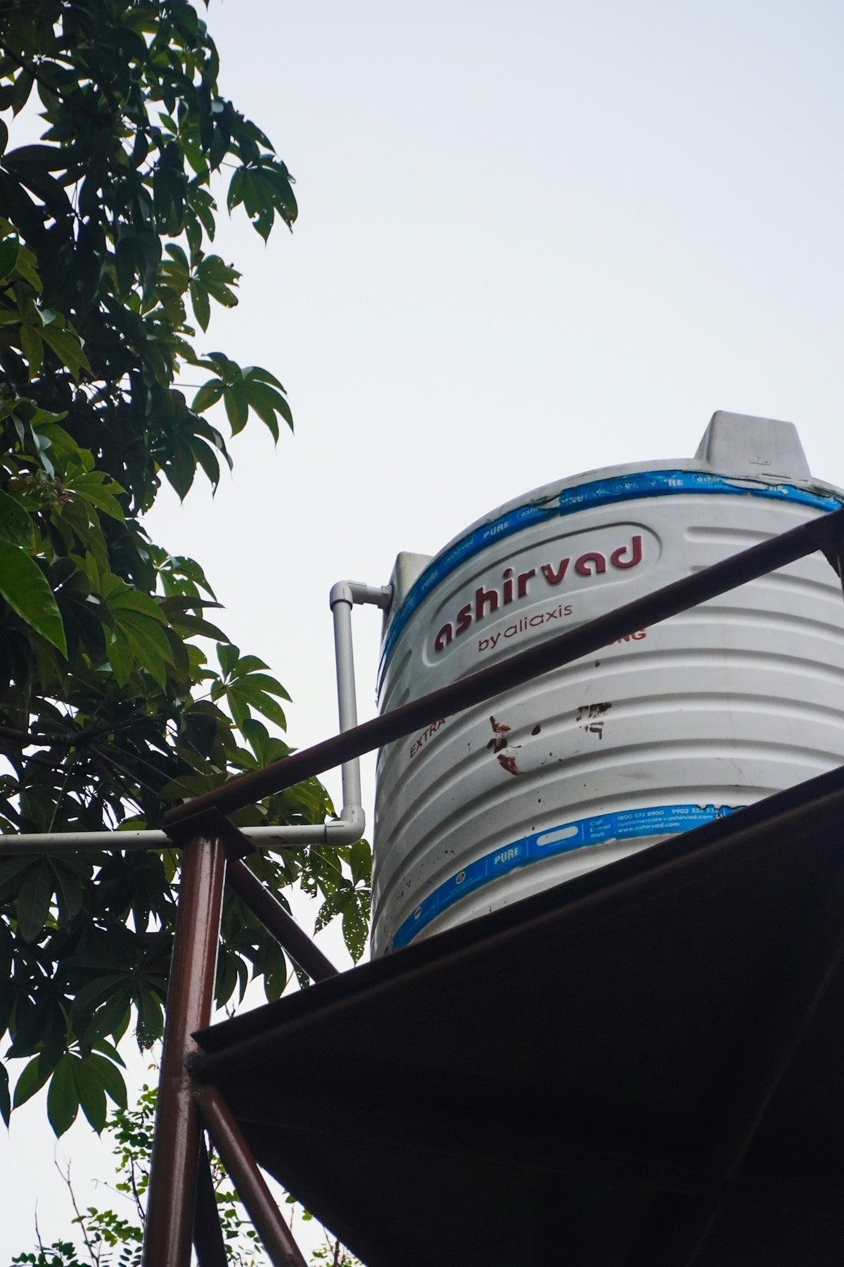 Water tank with green leaves and overcast sky.